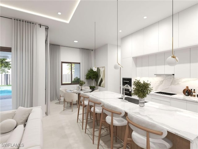 kitchen featuring white cabinetry, black electric stovetop, pendant lighting, and light stone counters