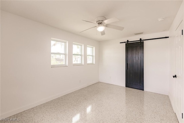 empty room featuring a barn door and ceiling fan