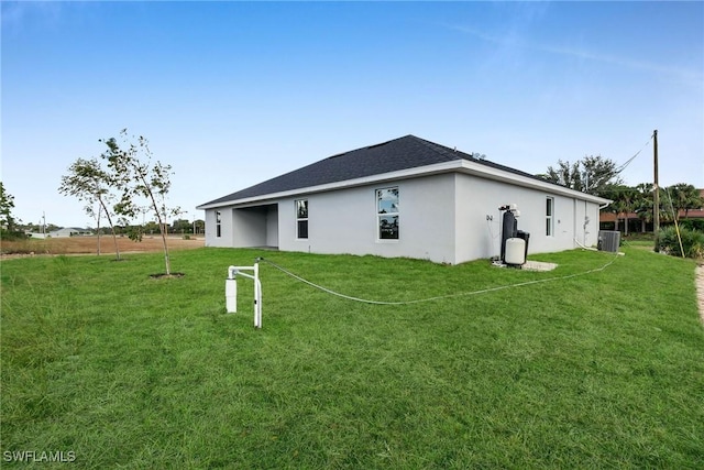 back of house with central AC unit and a lawn