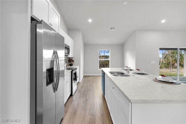 kitchen featuring appliances with stainless steel finishes, sink, a center island with sink, light hardwood / wood-style flooring, and white cabinets