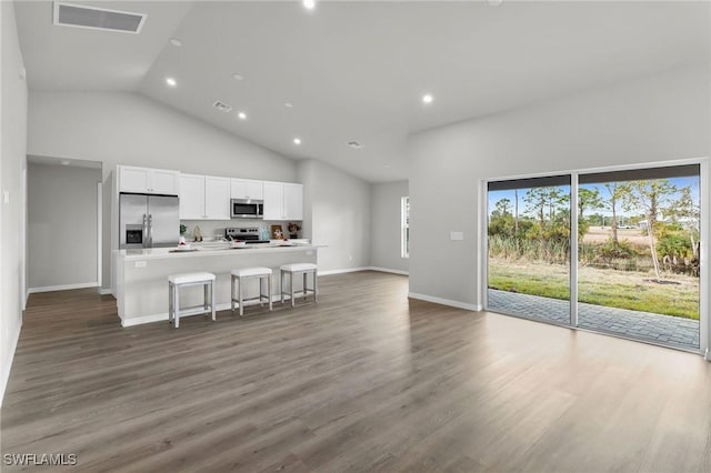 kitchen featuring dark hardwood / wood-style flooring, an island with sink, a breakfast bar, white cabinets, and appliances with stainless steel finishes