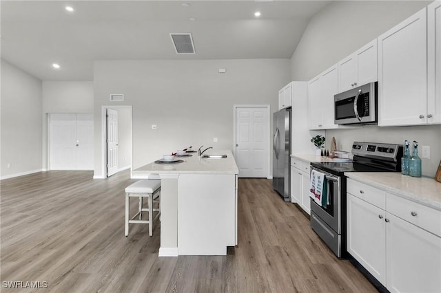 kitchen with a kitchen island with sink, sink, white cabinets, and appliances with stainless steel finishes