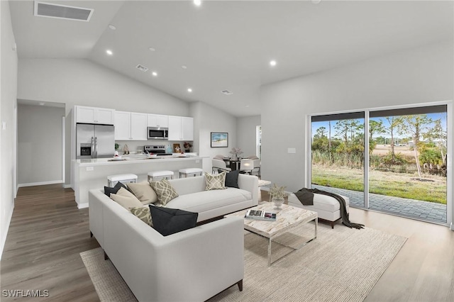 living room with high vaulted ceiling and light hardwood / wood-style flooring