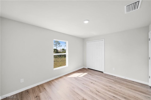 unfurnished bedroom with a closet, visible vents, light wood-style flooring, and baseboards