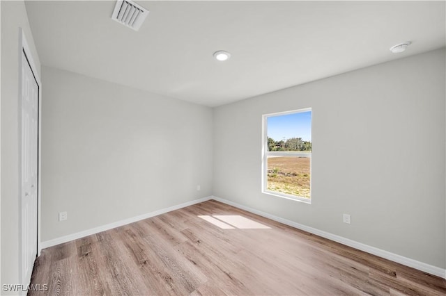 unfurnished room with wood finished floors, visible vents, and baseboards