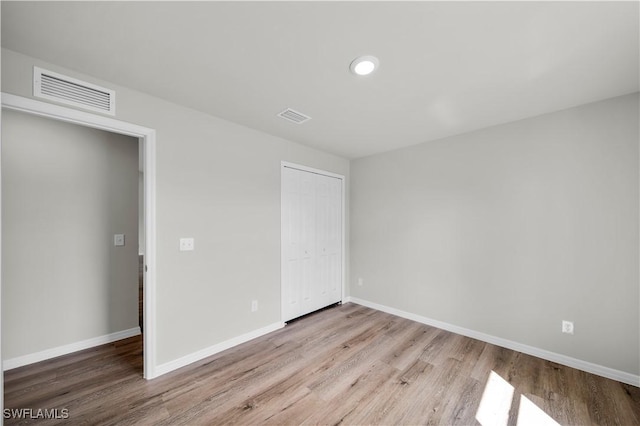 unfurnished bedroom featuring a closet, visible vents, baseboards, and wood finished floors