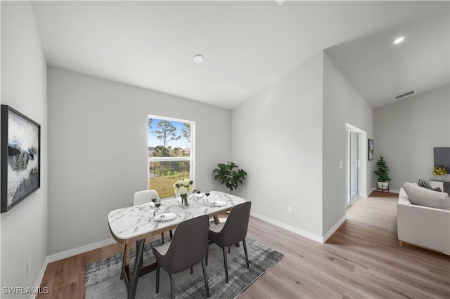 dining area with lofted ceiling, wood finished floors, visible vents, and baseboards