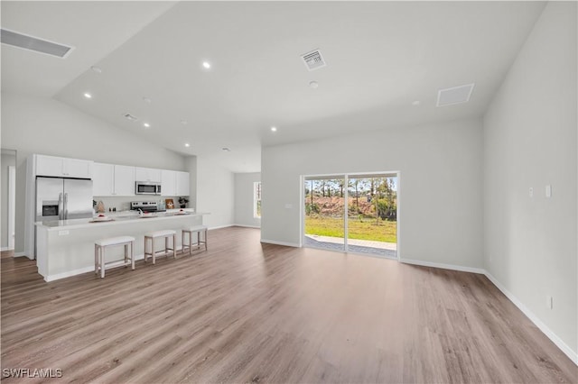 living area featuring recessed lighting, visible vents, light wood-style floors, high vaulted ceiling, and baseboards