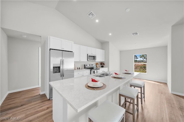 kitchen featuring appliances with stainless steel finishes, white cabinets, visible vents, and light wood-style floors