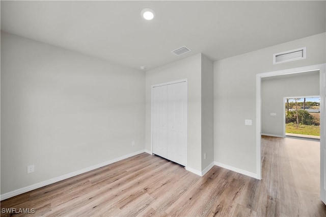 unfurnished bedroom with baseboards, a closet, visible vents, and wood finished floors