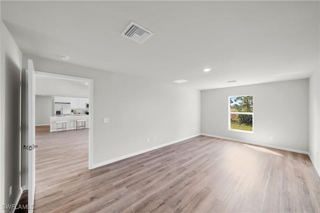 unfurnished room featuring light wood finished floors, baseboards, and visible vents