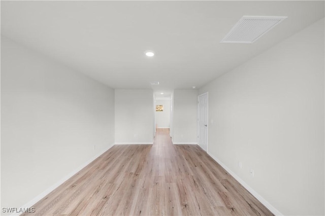 empty room featuring light wood finished floors, recessed lighting, visible vents, and baseboards