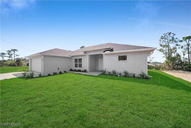 view of front facade featuring a garage, driveway, a front yard, and stucco siding