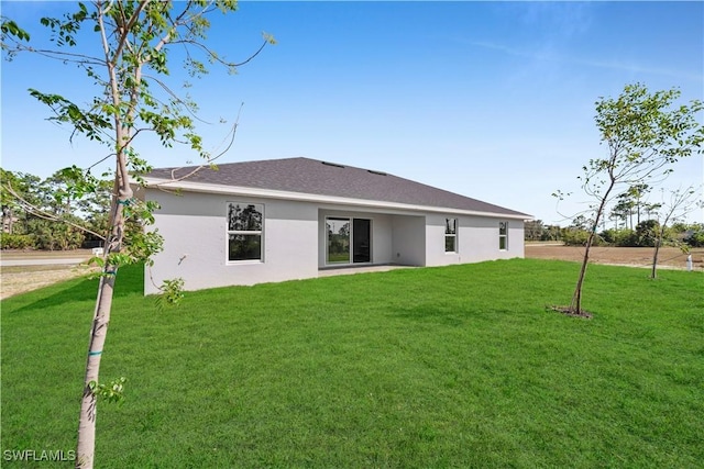 rear view of house featuring stucco siding and a yard