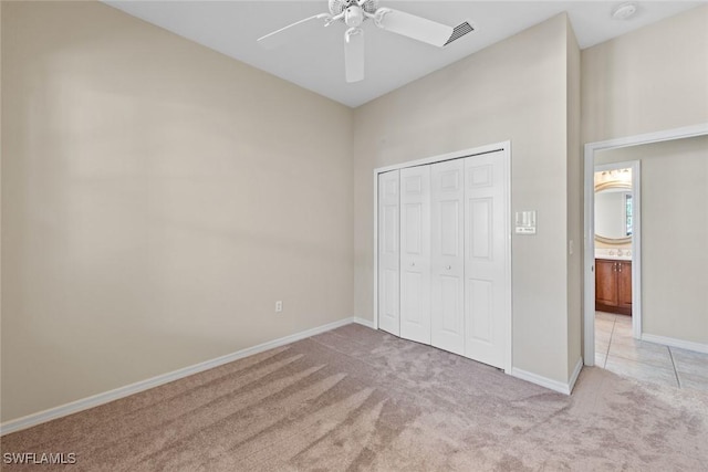 unfurnished bedroom featuring light carpet, a closet, and ceiling fan