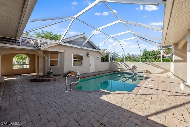 view of pool with glass enclosure and a patio