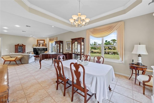 dining space featuring a raised ceiling, light tile patterned floors, ceiling fan with notable chandelier, and ornamental molding