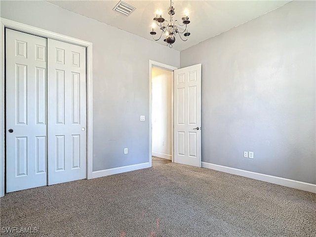 unfurnished bedroom with carpet flooring, a notable chandelier, and a closet