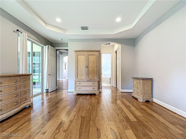 unfurnished bedroom featuring hardwood / wood-style floors, a tray ceiling, and access to outside