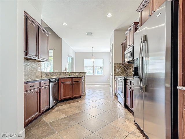 kitchen with tasteful backsplash, stainless steel appliances, light stone counters, and hanging light fixtures