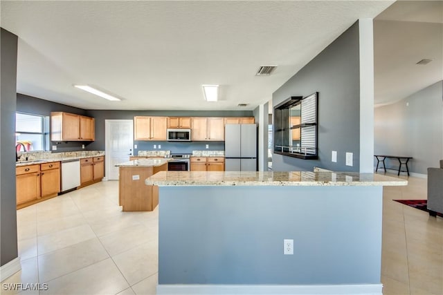 kitchen with light stone countertops, sink, a center island, stainless steel appliances, and kitchen peninsula