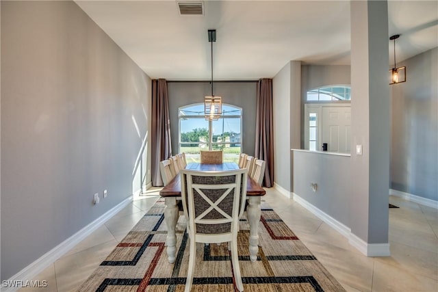 tiled dining space featuring a notable chandelier and a healthy amount of sunlight