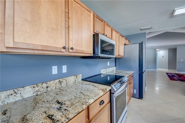 kitchen with light stone countertops, light brown cabinets, stainless steel appliances, a textured ceiling, and light tile patterned flooring