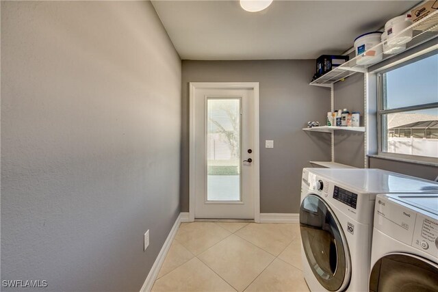 clothes washing area with light tile patterned flooring, a healthy amount of sunlight, and independent washer and dryer