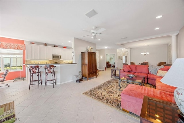 living room with light tile patterned floors, ceiling fan with notable chandelier, and ornate columns