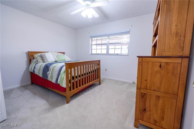 bedroom featuring a textured ceiling, light colored carpet, and ceiling fan