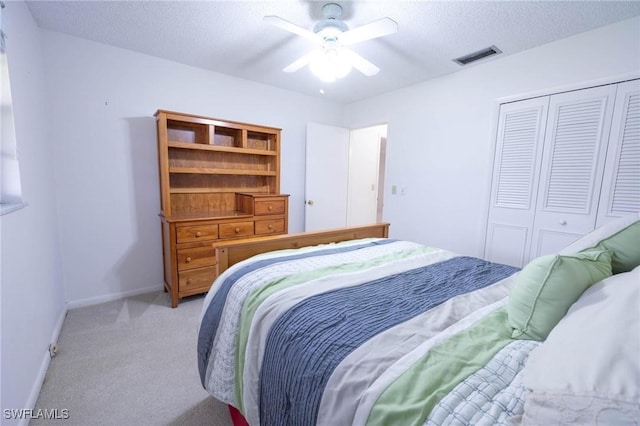 carpeted bedroom featuring ceiling fan, a textured ceiling, and a closet