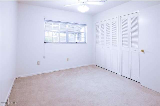 unfurnished bedroom featuring light carpet, two closets, and ceiling fan