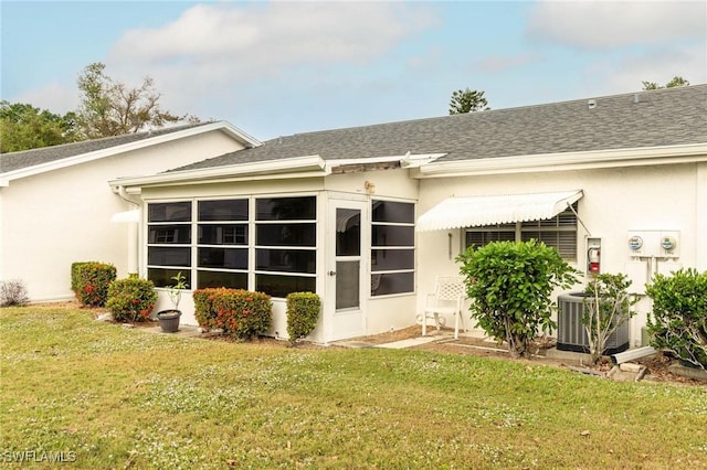 rear view of property with a lawn and central air condition unit