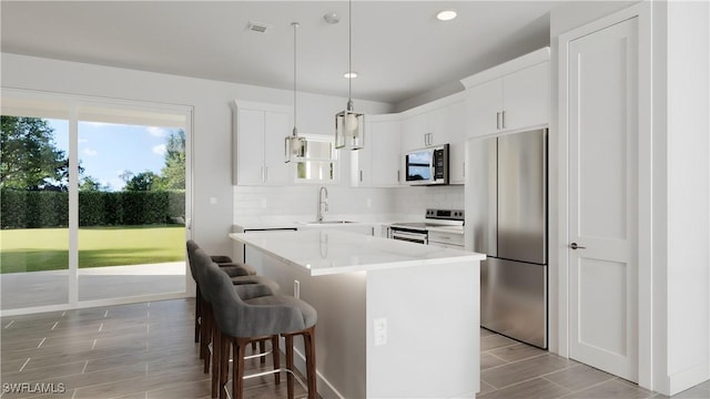 kitchen with pendant lighting, a center island, sink, white cabinetry, and stainless steel appliances