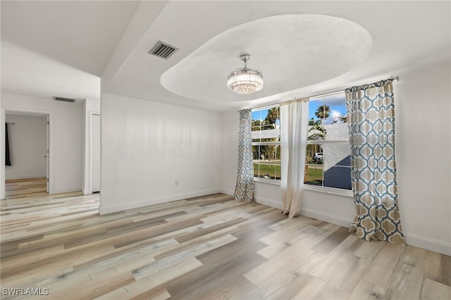 empty room with an inviting chandelier and light hardwood / wood-style flooring