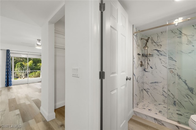 bathroom featuring ceiling fan, wood-type flooring, and a shower with shower door