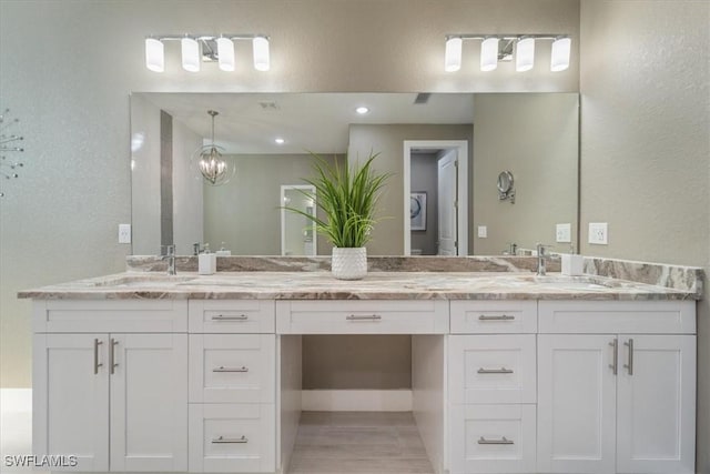 full bathroom featuring double vanity, a textured wall, and a sink