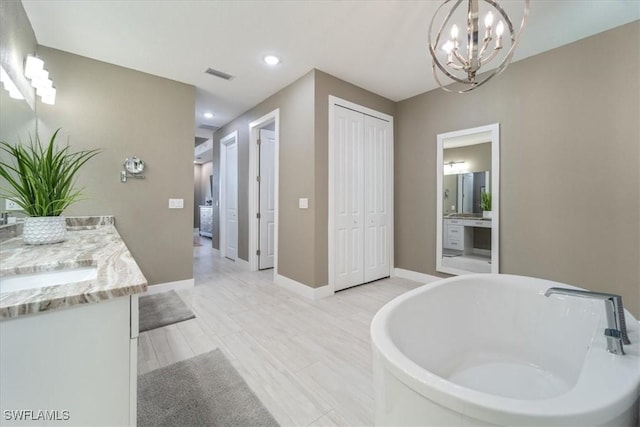 full bathroom featuring visible vents, an inviting chandelier, baseboards, a soaking tub, and vanity