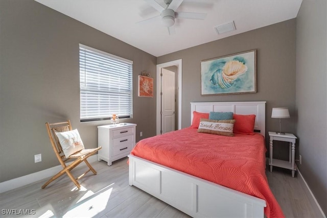 bedroom with visible vents, a ceiling fan, baseboards, and light wood finished floors