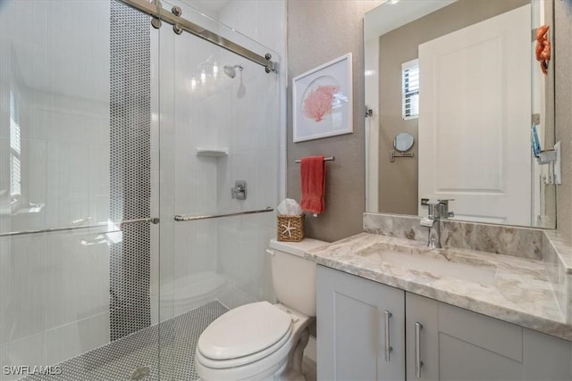 full bathroom featuring a stall shower, toilet, and vanity