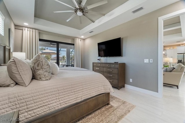 bedroom featuring baseboards, visible vents, a tray ceiling, light wood-style flooring, and recessed lighting