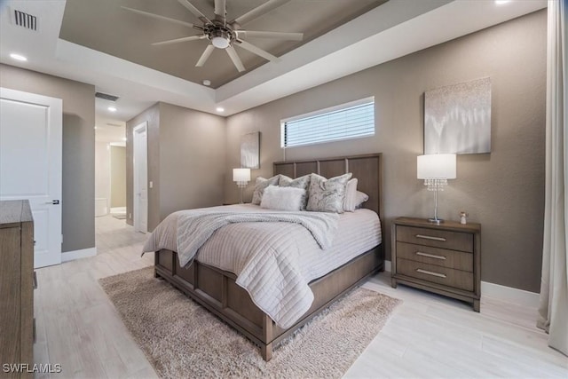 bedroom with visible vents, a raised ceiling, and baseboards