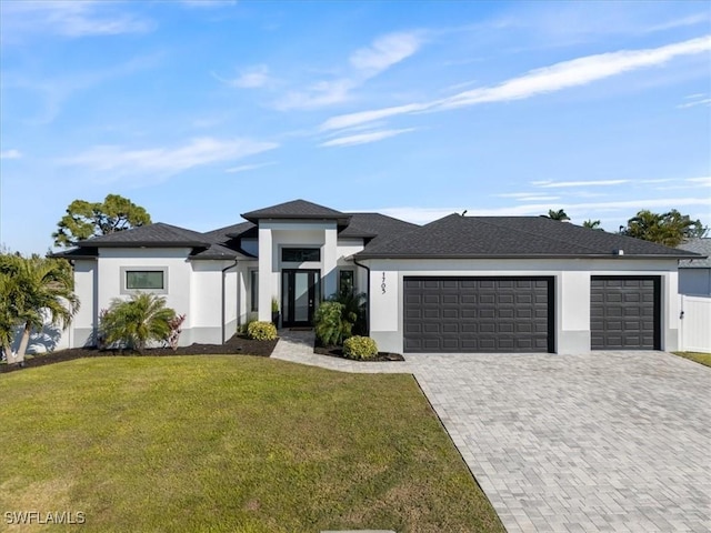 prairie-style home with a front lawn, decorative driveway, an attached garage, and stucco siding