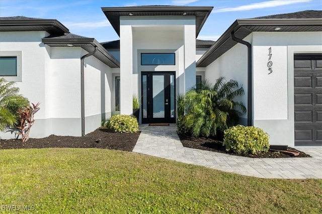 view of exterior entry featuring an attached garage, a yard, and stucco siding