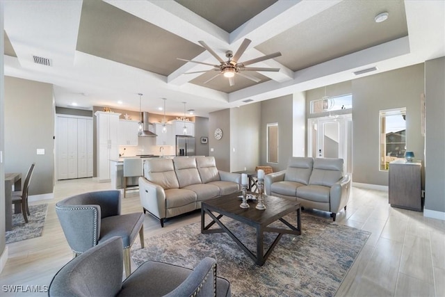 living room featuring a ceiling fan, baseboards, visible vents, and coffered ceiling