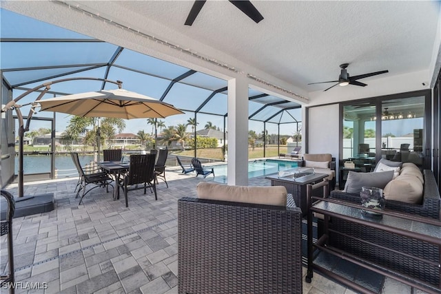 view of patio / terrace with a water view, glass enclosure, outdoor lounge area, an outdoor pool, and ceiling fan