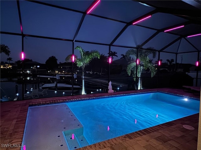 pool at twilight with a patio and a lanai