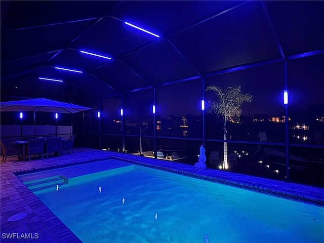 pool at twilight featuring glass enclosure, a patio, and an outdoor pool