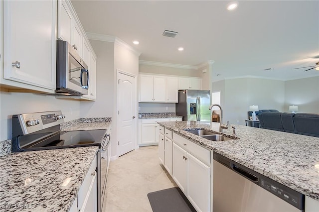 kitchen featuring sink, light stone counters, appliances with stainless steel finishes, white cabinets, and ornamental molding