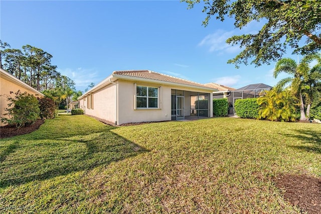 back of property featuring a lanai and a lawn